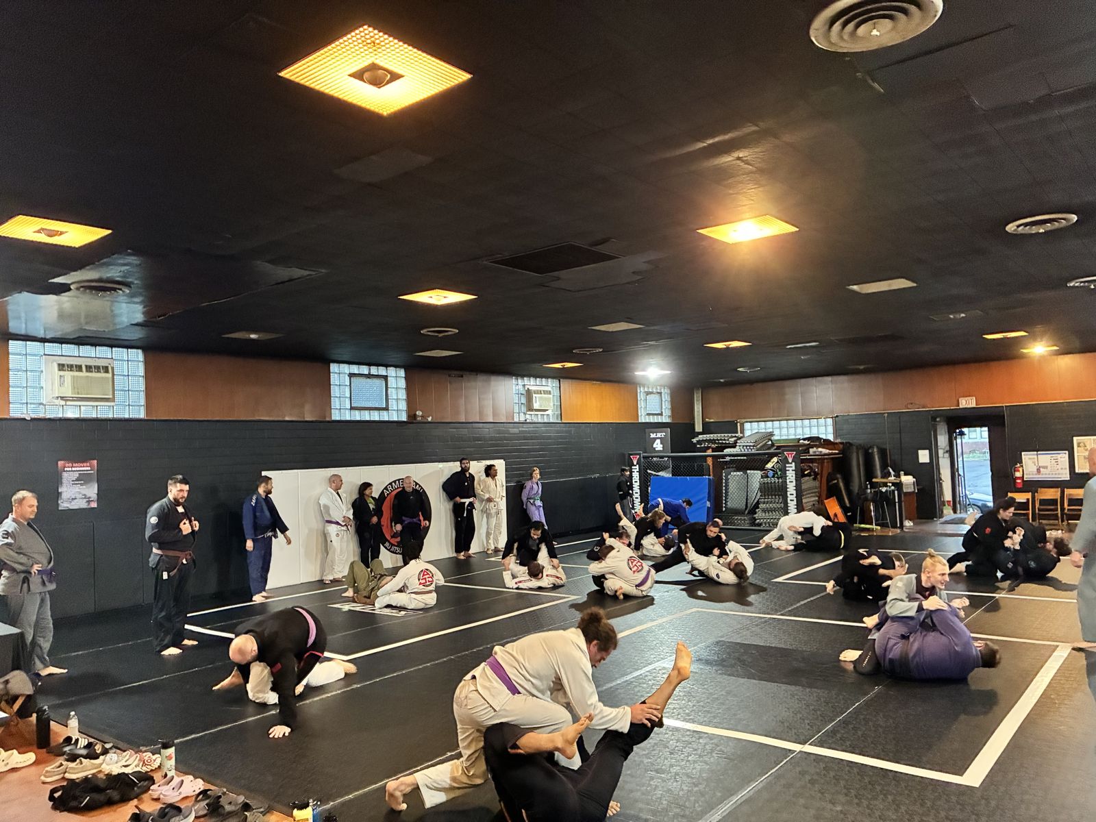 Adult class rolling across the mats in front of the Armezzani logo