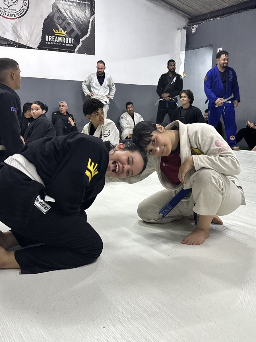 Training partners laughing on the mat under the Projeto Arte Suave banner