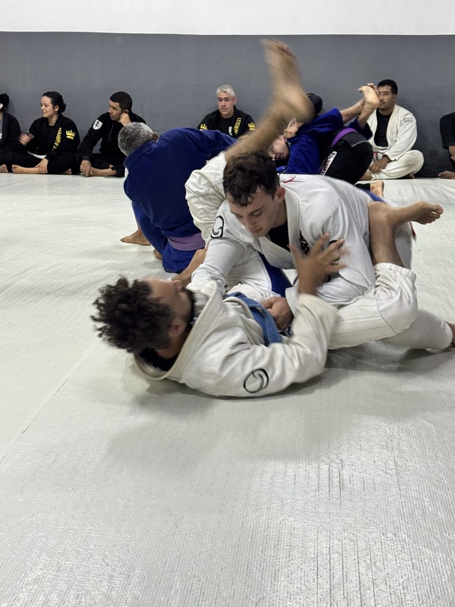 Two students in white and blue gis rolling in Brazil