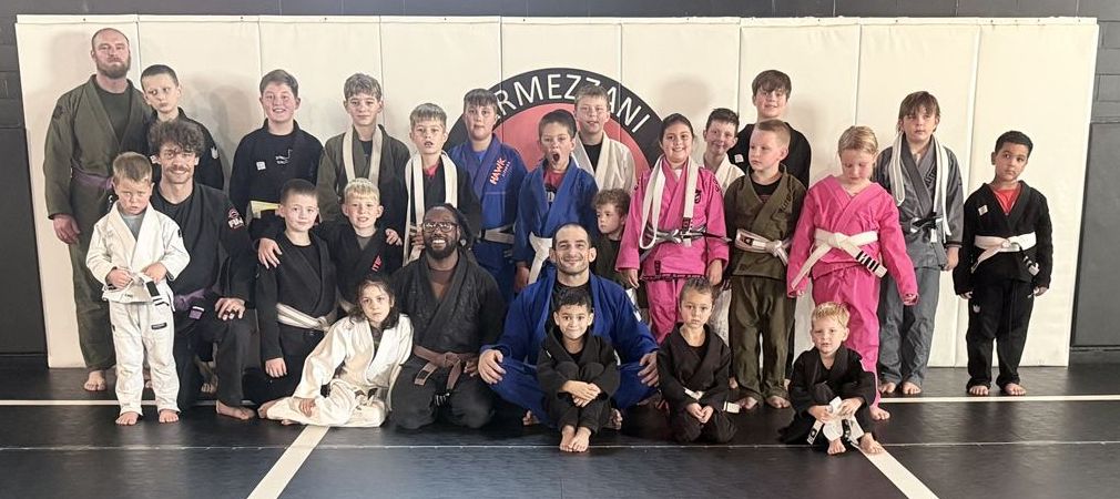 Big kids class group photo in front of the academy logo