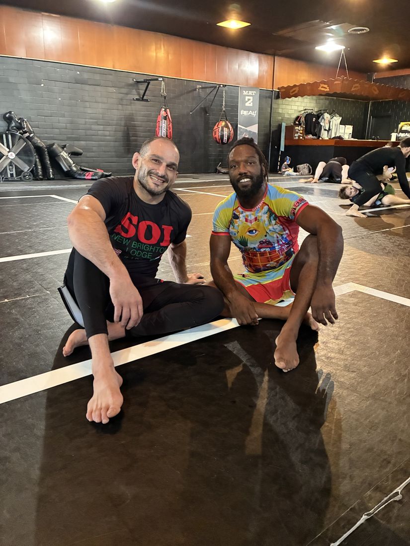 Two training partners smiling on the mat after no-gi rounds